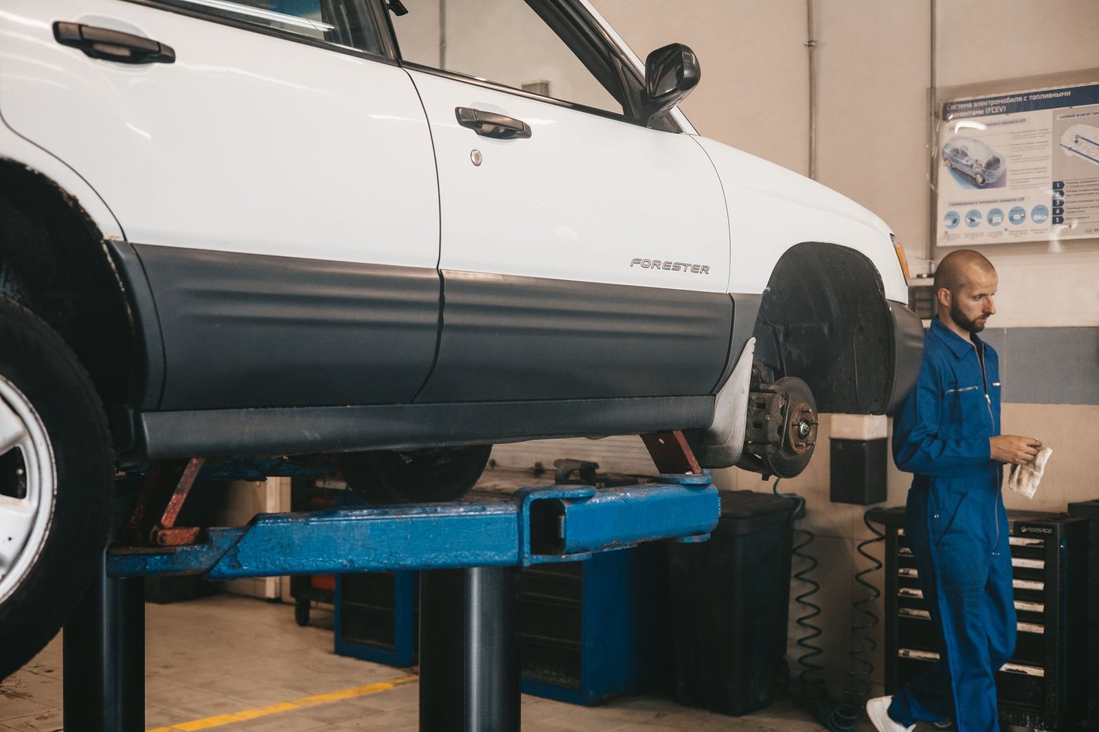 A mechanic inspecting a car raised on a hoist in an auto repair workshop